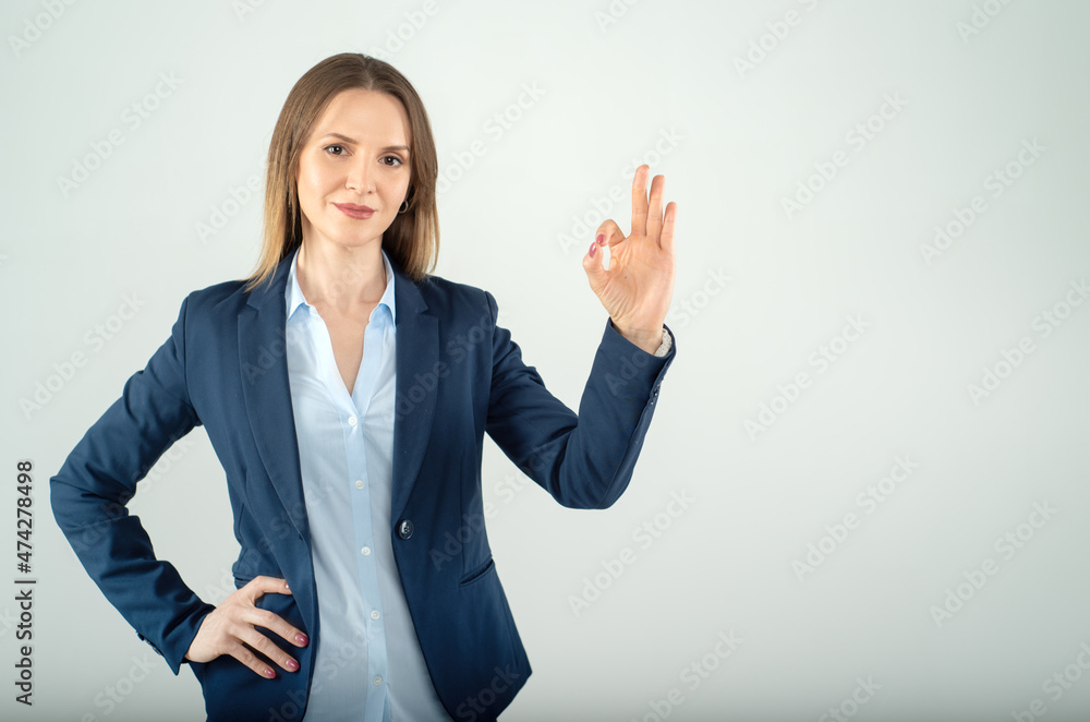 Young business lady shows OK sign isolated on grey background Young business lady shows OK sign isolated on grey background