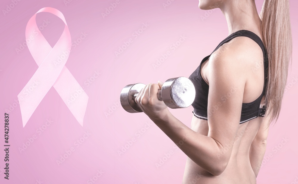 First person raised woman's hand holding a dumbbell and pink ribbon, symbol of breast cancer awareness First person raised woman's hand holding a dumbbell and pink ribbon, symbol of breast cancer awareness