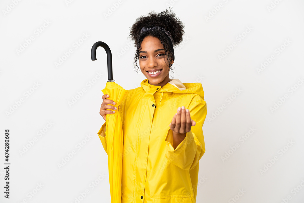 Young woman with rainproof coat and umbrella isolated on white background inviting to come with hand. Happy that you came Young woman with rainproof coat and umbrella isolated on white background inviting to come with hand. Happy that you came