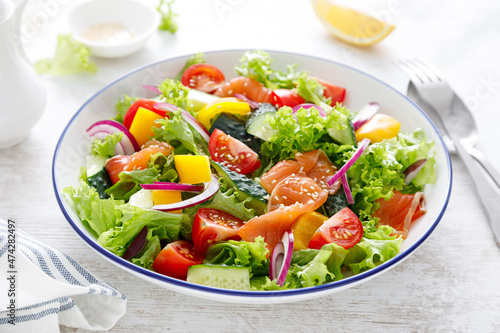 Salted salmon salad with fresh green lettuce, cucumbers, tomato, bell pepper and red onion. Ketogenic, keto or paleo diet lunch bowl
