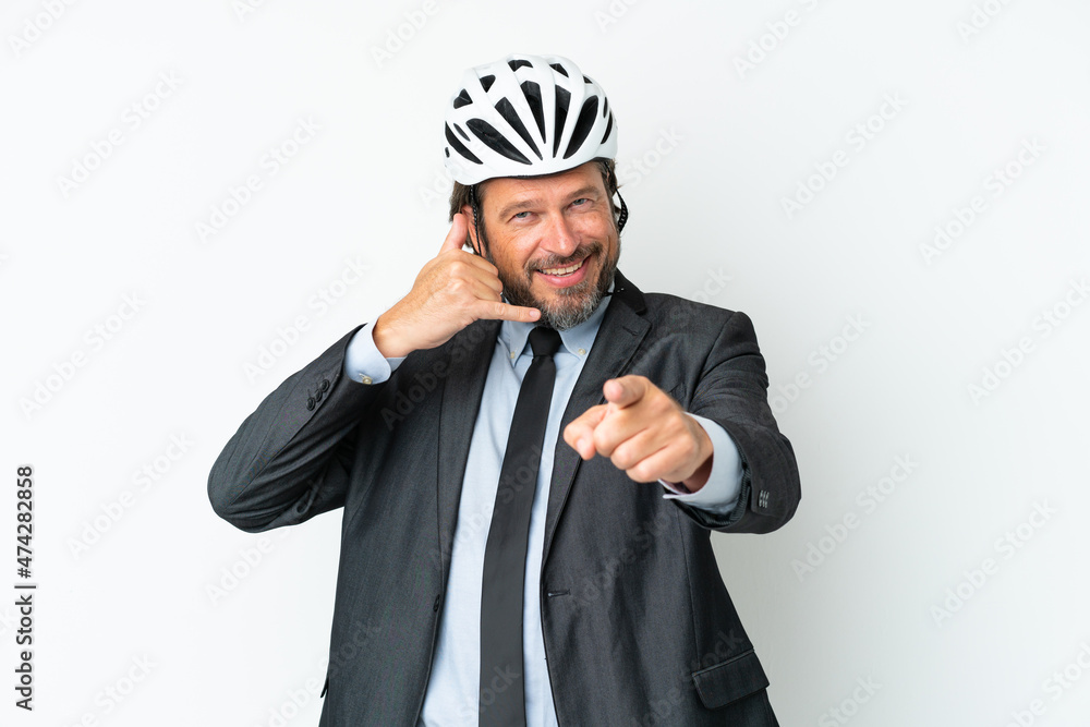 Business senior man with a bike helmet isolated on white background making phone gesture and pointing front Business senior man with a bike helmet isolated on white background making phone gesture and pointing front