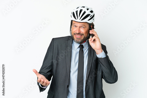 Business senior man with a bike helmet isolated on white background keeping a conversation with the mobile phone with someone © luismolinero