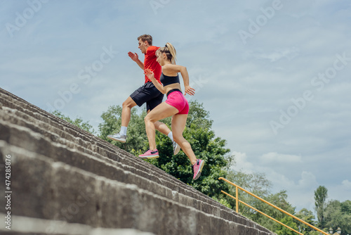 Healthy active couple exercising cardio and sprinting staircase in a park.