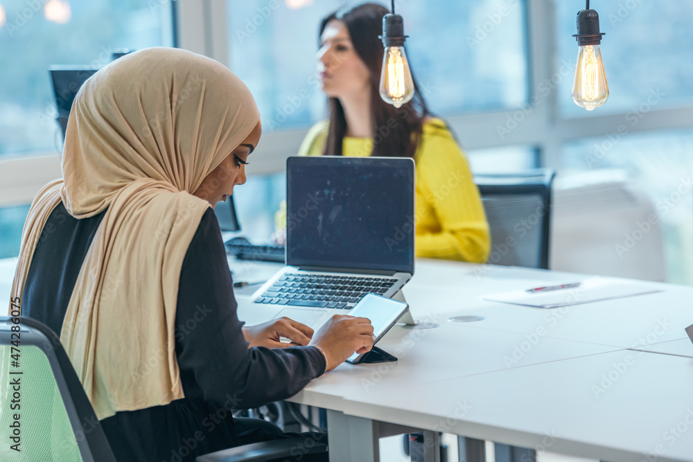 Business education and office concept. African American businesswoman wearing a hijab working, typing on a pc ( computer). Female entrepreneur sitting on her desk..