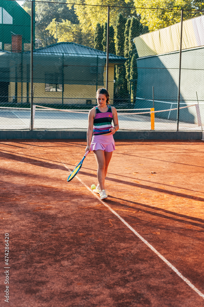 A young female tennis player serving on a clay court