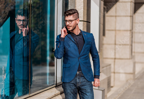 Side view of a happy man calling on the phone walking on the street