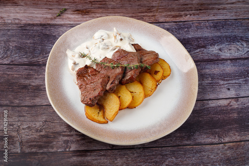 Thick juicy portions of grilled beef fillet with mushroom sauce served with thyme potatoes