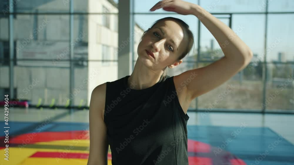 Portrait of young sportswoman stretching neck and arms doing warm-up exercises in modern gym. Healthy lifestyle and wellbeing concept. Portrait of young sportswoman stretching neck and arms doing warm-up exercises in modern gym. Healthy lifestyle and wellbeing concept.