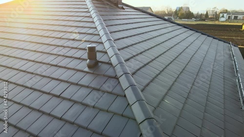 Closeup of ventilation pipe on house roof top covered with ceramic shingles. Tiled covering of building photo
