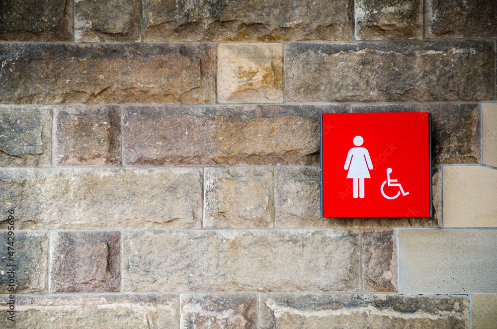 Red female toilet and disabled accessible sign on the old stone brick wall. Red female toilet and disabled accessible sign on the old stone brick wall.