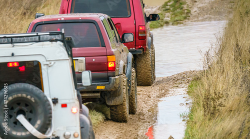 4x4 off-road vehicles driving across mud, water-logged terrain and wading through deep water pools, Wilts UK. Land Rover Discovery, Defender and Toyota 4Runner Hilux Surf © Martin