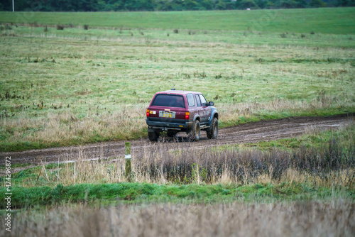 Toyota Hilux Surf 4Runner 4x4 off-road vehicle driving across mud, water-logged terrain and wading through deep water pools, Wilts UK.  © Martin