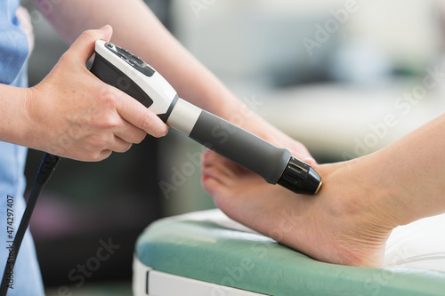 Surgery and Medical theme: Shock wave therapy. The magnetic field, rehabilitation. Physiotherapist doctor performs surgery on a patient's leg, knee, ankle.