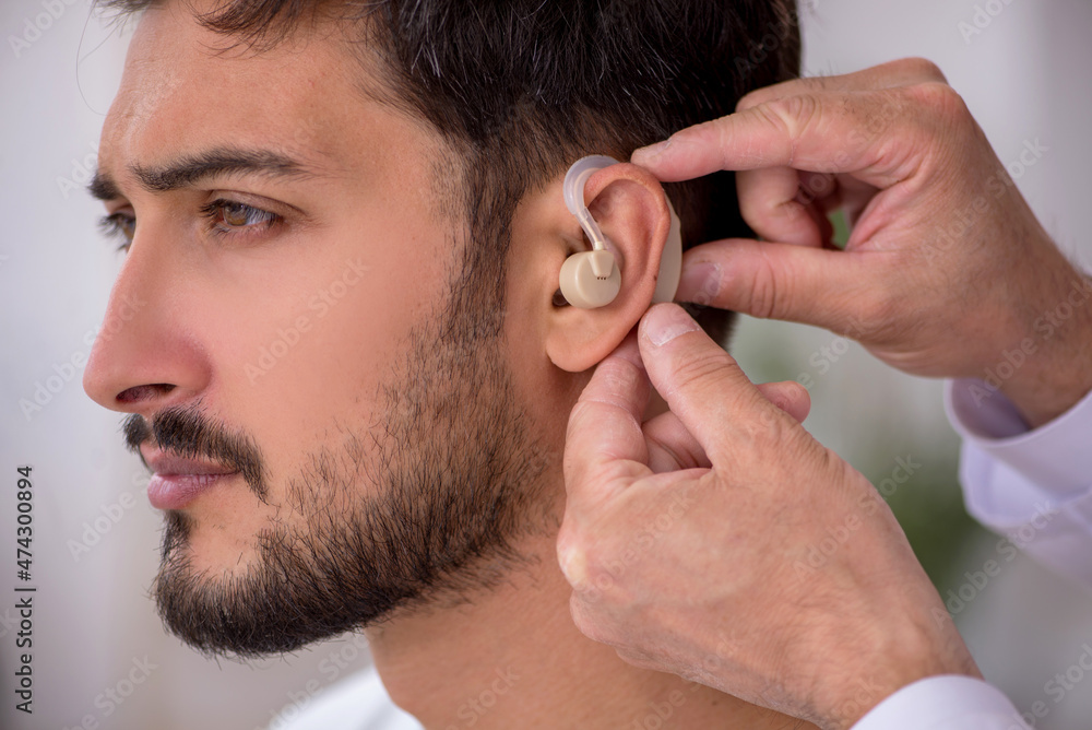 Obraz premium Young male patient with hearing problem visiting old doctor otor