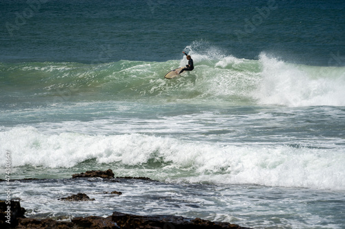 male surfer catching waves surfing at south coast beach on a bright warm sunny day on clear blue water