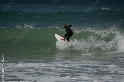 male surfer catching waves surfing at south coast beach on a bright warm sunny day on clear blue water © Em Neems Photography