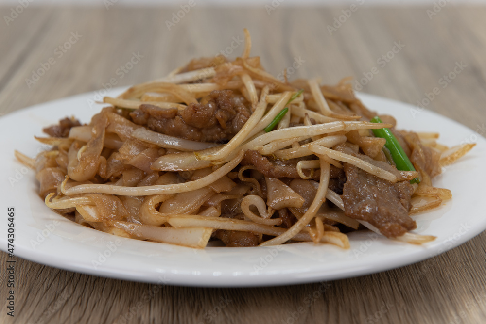 Beef chow mein noodles makes an enormous pile on the plate for a delicious Chinese food experience Beef chow mein noodles makes an enormous pile on the plate for a delicious Chinese food experience