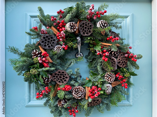 Christmas mood. Elegant christmas wreath decorated red berries, pine cones and lotus on a blue wooden door