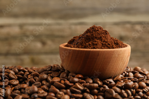 Bowl of ground coffee on roasted beans, closeup