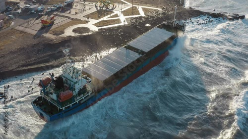 A large seagoing vessel dry cargo ship washed ashore during a strong storm wind and ran aground. The dry cargo ship washed ashore during a sea storm. Oil spills. A sea-going cargo ship washed ashore 