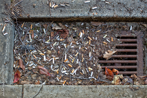 Gutter drain after rain full of cigarette butts