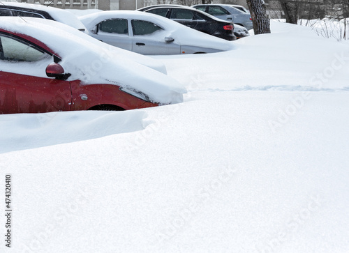 parked cars covered with snow after blizzard in winter time