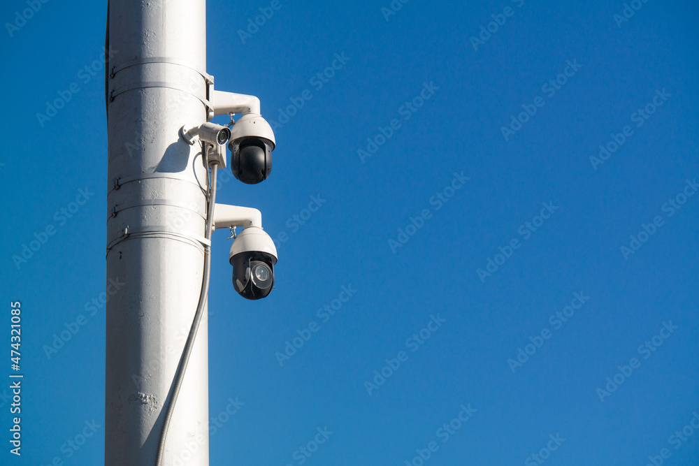 Modern cameras on a white pole against blue sky Modern cameras on a white pole against blue sky