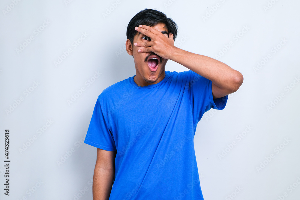 Man peeking in shock covering face and eyes with hand, looking through fingers with embarrassed expression. Man peeking in shock covering face and eyes with hand, looking through fingers with embarrassed expression.
