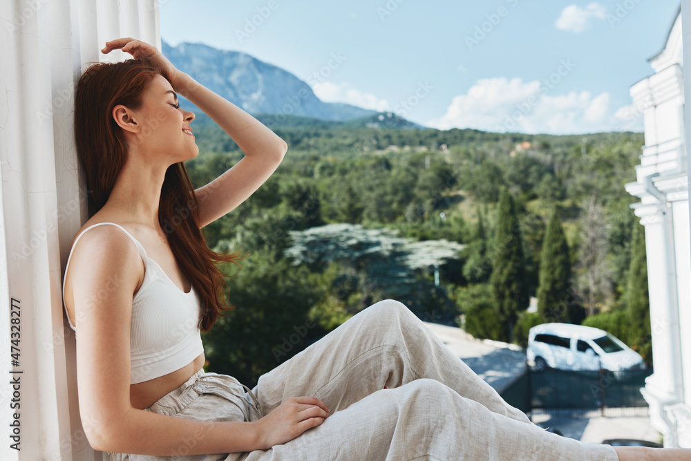 Attractive young woman sitting on the balcony beautiful mountain view summer Perfect sunny morning