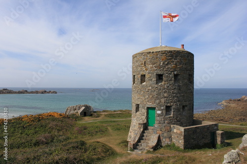 A loophole tower on the coast of Guernsey with the Guernsey Flag flying photo