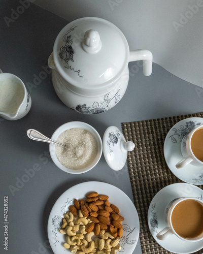 Tea time with Biscuits and dry fruits, White Plan Cashew, and Almonds.
seave in the white marble Tea set.  photo