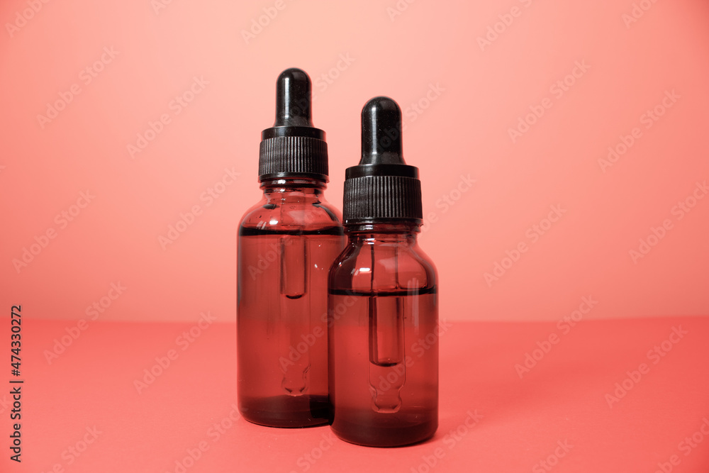 Glass dropper bottle with a pippette with black rubber tip on pink background. Nature Skin concept. Organic Spa Cosmetics. Trendy concept.