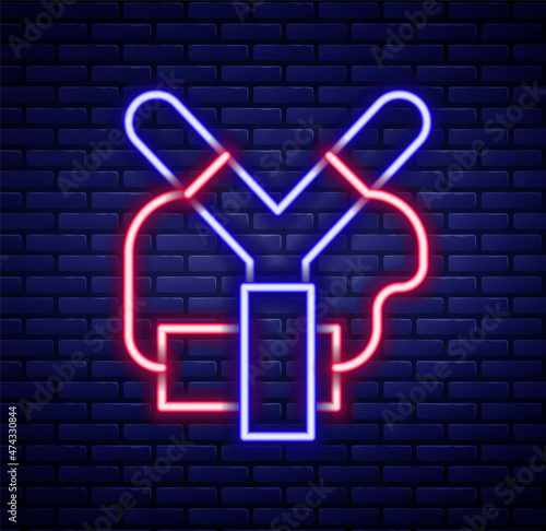 Glowing neon line Slingshot icon isolated on brick wall background. Colorful outline concept. Vector