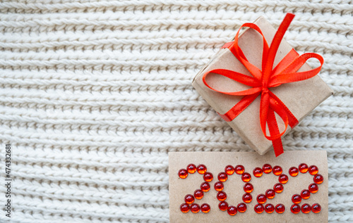 Happy New Year and Christmas 2022. Red numbers and gift on cozy background. Celebrating holidays, shopping presents. Flatly, top view. 