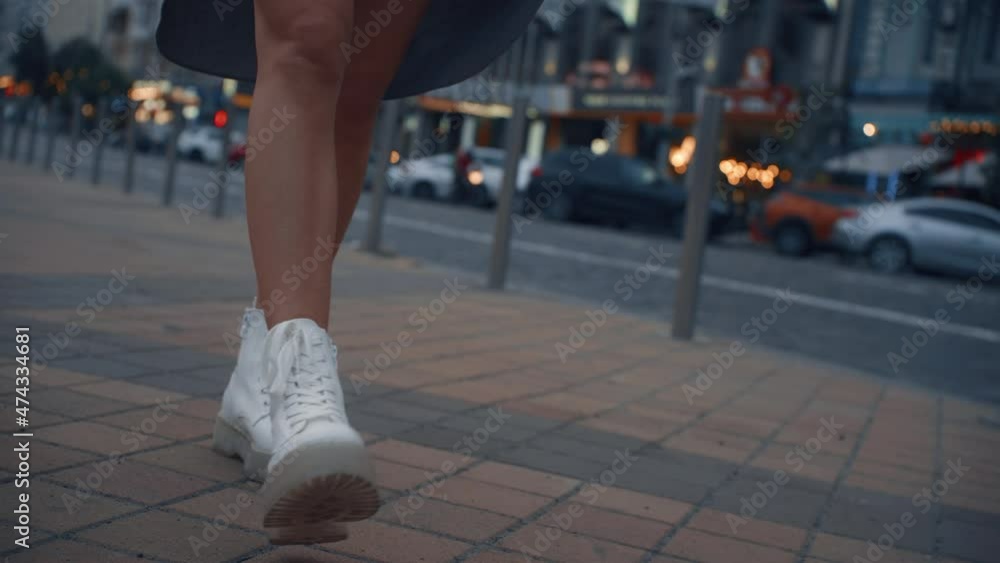 Female legs walking down road at evening city near highway traffic lights. Female legs walking down road at evening city near highway traffic lights.