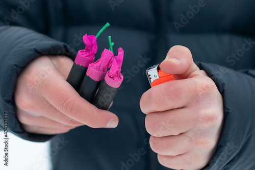 Guy Sets Fire to the Flash Noise Firecrackers Outdoors in Winter at Daytime. Loud and Dangerous New Year's Entertainment. Hooliganism with Pyrotechnics. Noise of Petards in Public Places