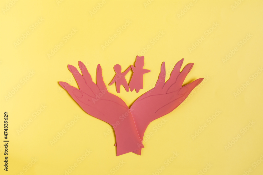 Obraz premium Cardboard figures hold small children with open palms of their hands. The concept of family and child protection