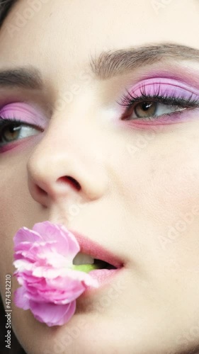 Closeup slow motion vertical video of female with a pink carnation in mouth. photo