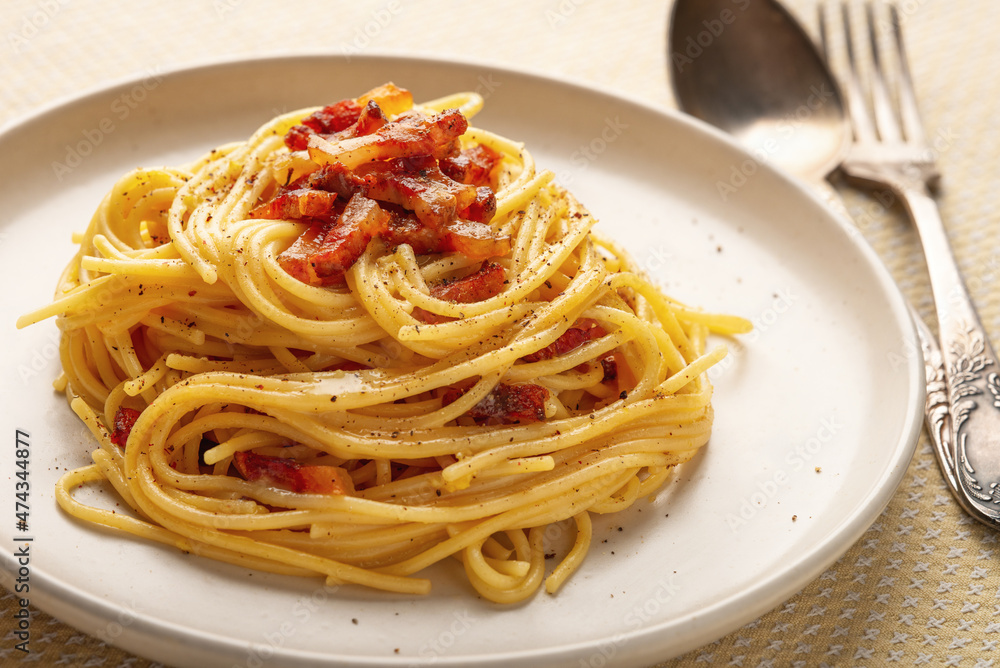 Close-up spaghetti carbonara in a plate with cutlery