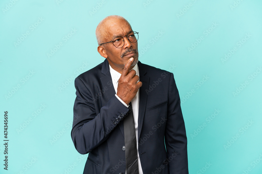 Business senior man isolated on blue background having doubts while looking up Business senior man isolated on blue background having doubts while looking up