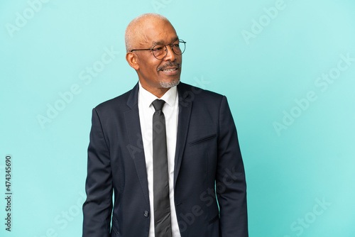 Business senior man isolated on blue background looking side