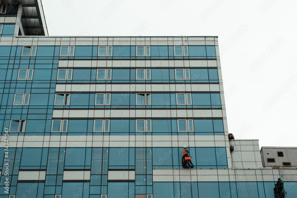 Obraz premium Working cleaning windows of high-rise building, outside. Industrial climbers