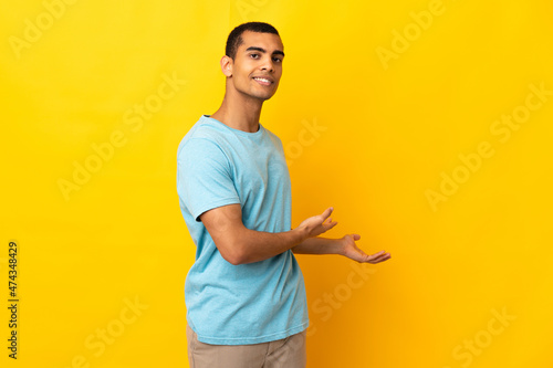 African American man over isolated background extending hands to the side for inviting to come © luismolinero