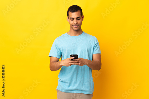 African American man over isolated background sending a message with the mobile © luismolinero