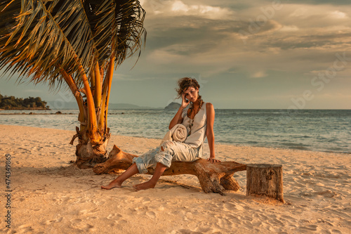 beautiful young woman on the beach of tropical resort at sunset