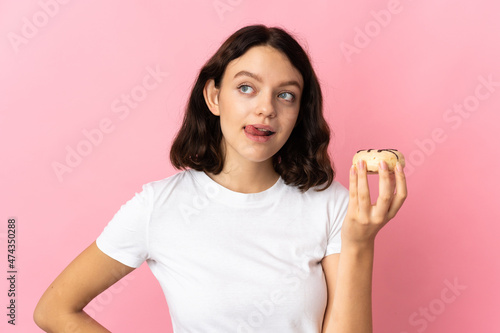 Teenager Ukrainian girl isolated on pink background holding a donut