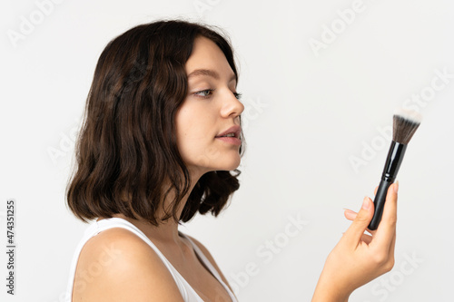 Teenager Ukrainian girl isolated on white background holding makeup brush