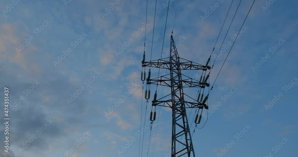 Hyperlapse of beautiful white clouds at dawn running past an iron power line with wires.
