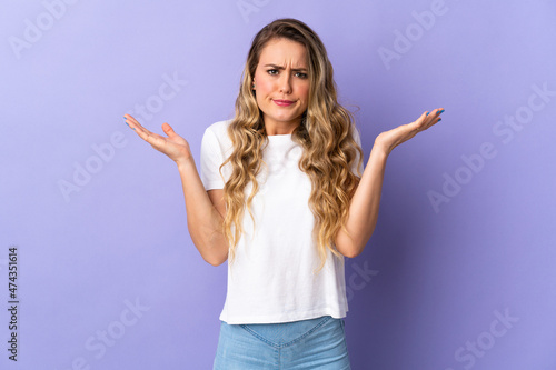 Young Brazilian woman isolated on purple background having doubts while raising hands