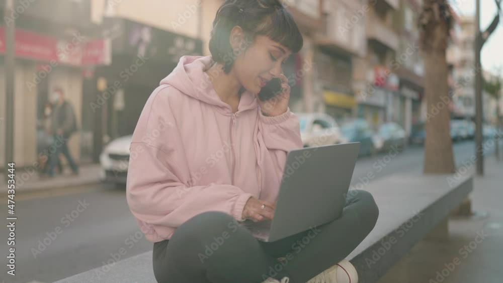 Young hispanic woman using laptop and talking on the smartphone at street Young hispanic woman using laptop and talking on the smartphone at street